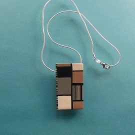 S344 This rectangular pendant has a muted Mondrian style design in in black white grey and beige. It measures 2" x 1" and is suspended on an 46 cm (18 inches) snake chain.
